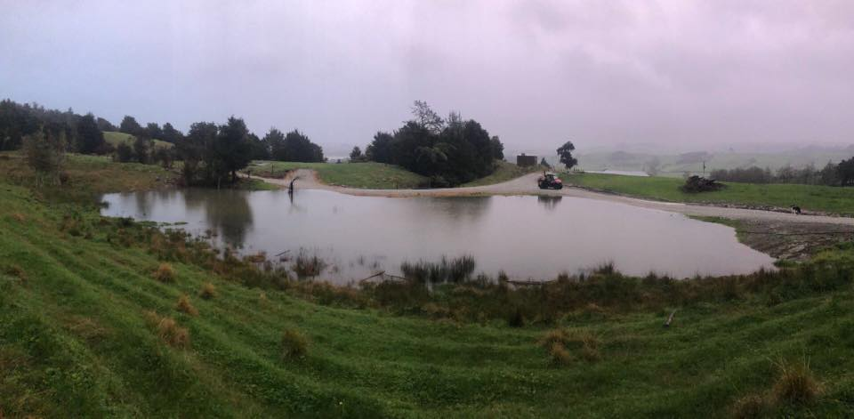 Long view of surface flooding blocked by a gravel road.