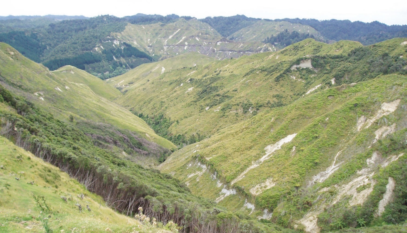 Long shot of grassed hills and white/grey canals where errosion has occured.